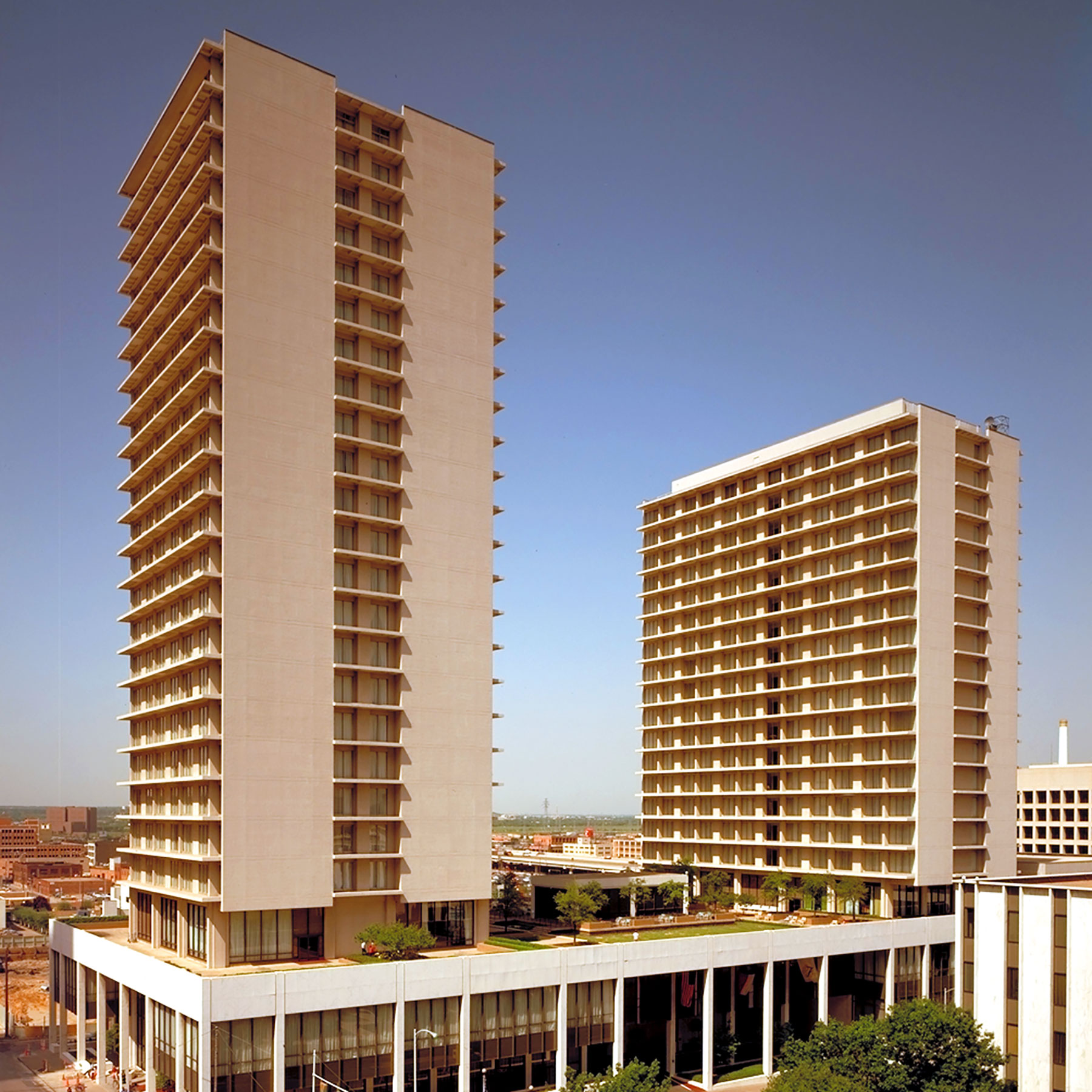 A one-tower hotel and an adjacent apartment building tied together at a landscaped terrace level with a courtyard. 